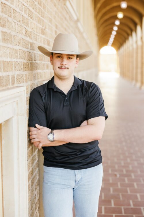 Man in cowboy hat leaning against brick wall